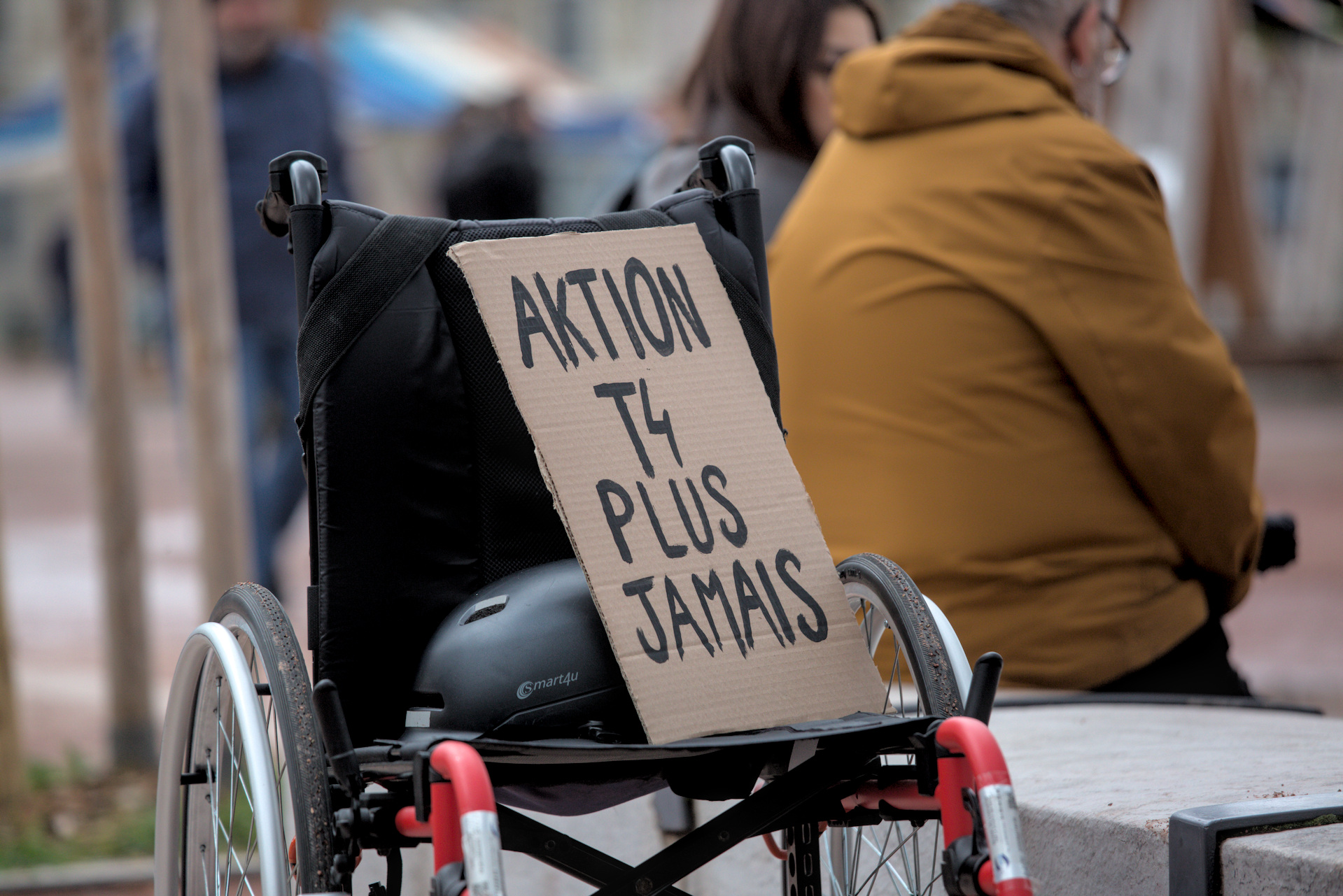 Pancarte « Aktion T4 plus jamais » posée sur un fauteuil roulant.